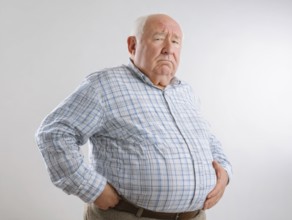 Elderly overweight man looks worried and holds his hands on his stomach, AI generated, AI generated