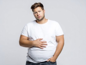 Overweight young man looks worried and holds his hand on his stomach, AI generated, AI generated