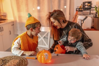 Mother and children wearing halloween costumes are sitting at a table in their kitchen, playing