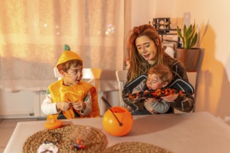 Mother and children wearing halloween costumes and painted faces, celebrating at home with candies