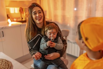 Mother holding her baby dressed up as a bat while smiling at her other child dressed in orange