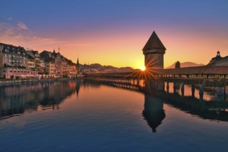 Chapel bridge with water tower reflected in the river Reuss at sunrise, view of Lucerne old town,