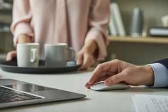 Woman holding a tray with white coffee mugs next to a man's hand on a large wireless mouse. Gender
