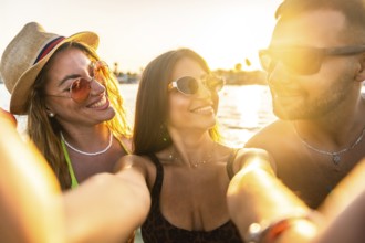 Cheerful young friends capturing a joyful selfie at the beach, reveling in the warmth of a summer