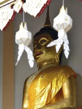 Majestic golden buddha statue wearing a yellow robe, serene and peaceful, inside a traditional thai