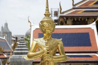 Majestic golden kinnara statue stands guard at wat phra kaew, the temple of the emerald buddha, a
