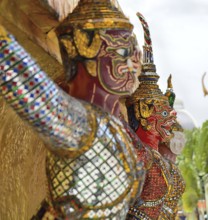 Giant colorful mosaic statues are guarding a thai temple, showcasing the intricate artistry and