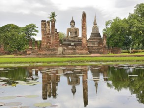 Serene buddha statue reflected in a pond at the sukhothai historical park, a unesco world heritage