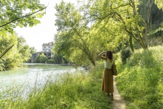 Woman enjoying a sunny day walking along the gave d'oloron river in sauveterre de bearn, a