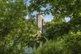 Green leaves frame a medieval bridge tower in sauveterre de bearn, france, creating a picturesque