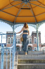 Tourist descending steps of colorful pavilion in salies de bearn, france, enjoying vacation and