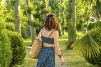 Tourist walking through a picturesque park in salies de bearn, france, carrying a tote bag and