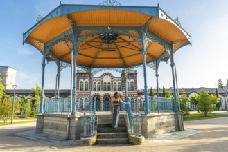 Tourist ascending stairs of a gazebo in a park in salies de bearn, france, enjoying a summer