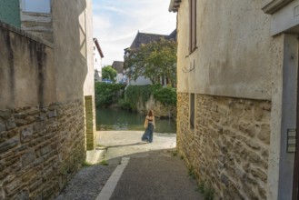 Tourist walking by the gave de salies river in the charming medieval village of salies de bearn, a
