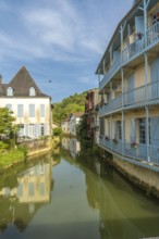Picturesque canal reflecting traditional houses with blue balconies in salies de bearn, a charming