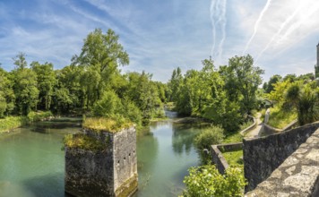 Scenic view of the gave d'oloron river with a ruined bridge pier and lush vegetation in sauveterre