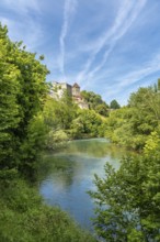 Lush vegetation surrounds the gave d'oloron river with sauveterre de bearn reflecting on the water