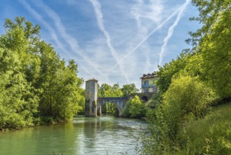 Scenic view of the historic stone bridge spanning the gave d'oloron river, with lush greenery and a
