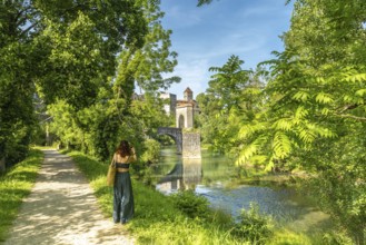 Tourist taking pictures of the gave d'oloron river and the medieval bridge and castle of sauveterre