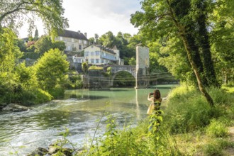 Tourist taking pictures of the gave d'oloron river and the old bridge in sauveterre de bearn, a