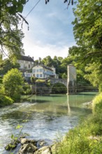 Scenic view of a historic stone bridge crossing the gave d'oloron river, surrounded by traditional