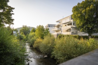 Residential building next to a river, surrounded by trees on a summer evening, Nagold, district of