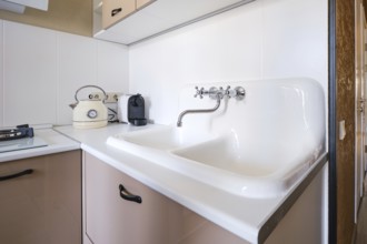 A clean kitchen space features a double sink with a vintage kettle beside a sleek coffee maker.