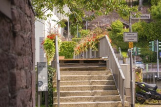 Stone staircase with floral decorations and signs, surrounded by urban architecture, small town of