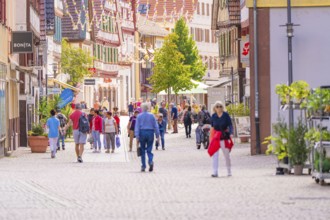 Lively pedestrian zone with people in a town with traditional half-timbered buildings and shops,