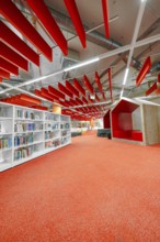 Modern library with red accents, bookshelves and comfortable reading corners, Munich, Germany