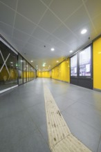 A modern station corridor with yellow walls and a grey floor conveys cleanliness, Munich, Germany