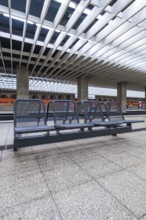 Modern railway station with benches and characteristic glass roof, Munich, Germany