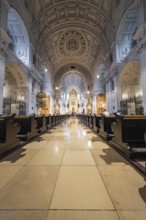 Magnificent church interior with long wooden benches, ornate altar and impressive dome, Munich,