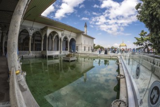 Tourists walking around the courtyard with reflecting pool of the topkapi palace in istanbul,