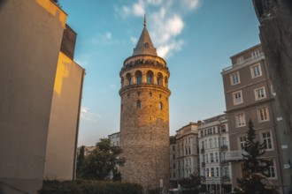 Galata tower, a medieval stone tower, is illuminated by the setting sun in istanbul, turkey,
