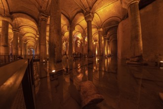 Warm lights illuminating columns and arches reflecting on the water surface of the basilica cistern