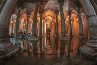 Ancient underground basilica cistern reflecting on water surface with tourists and medusa head