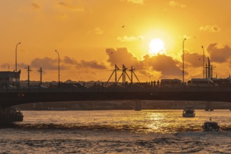 The golden horn waterway in istanbul, turkey, glows under a vibrant sunset, with a bridge full of