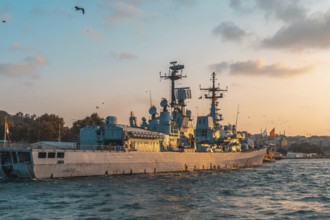 Modern warship gliding through the tranquil sea near istanbul, turkey, under a stunning golden hour