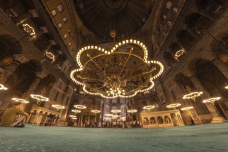 Tourists gather beneath the magnificent chandeliers within the hagia sophia, a historical landmark