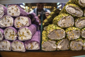 Colorful turkish delight lokum rolls, coated in pistachios and filled with walnuts, stacked on