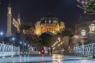 Tourists strolling in front of the hagia sophia mosque, beautifully illuminated at night, creating