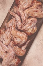 Chicken wings, marinated and laid out on a wooden platter, ready for cooking, grilling or baking,