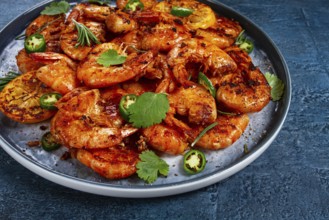 Grilled shrimp, unpeeled, headless, with spices, on a dark blue table, homemade, no people
