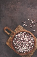 Variegated beans, red with white spots, raw in a wooden bowl, top view, no people