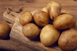 Raw potatoes, scattered on a chopping board, close-up, no people