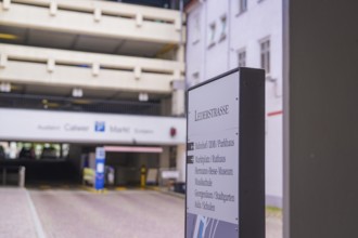 Signpost in front of a multi-storey car park in the old town, architecture in the background, small