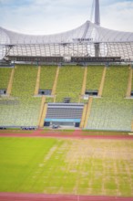 Detailed view of a stadium section with green seating area and roof structure in the background,