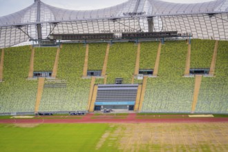 Detailed view of a stadium section with green rows of seats and striking roof background,