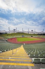 Symmetrical view of a stadium from a staircase with red running track and green stands, Olympic